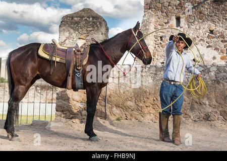 Un Mexicain charro ou pratiques cowboy roping compétences avec son cheval à une hacienda ranch dans Alcocer, au Mexique. La Charreada est une forme traditionnelle mexicaine de rodeo et teste les compétences de l'équitation à cowboy au lasso, et le contrôle du bétail. Banque D'Images