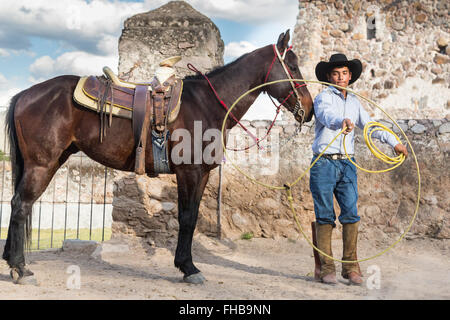 Un Mexicain charro ou pratiques cowboy roping compétences avec son cheval à une hacienda ranch dans Alcocer, au Mexique. La Charreada est une forme traditionnelle mexicaine de rodeo et teste les compétences de l'équitation à cowboy au lasso, et le contrôle du bétail. Banque D'Images