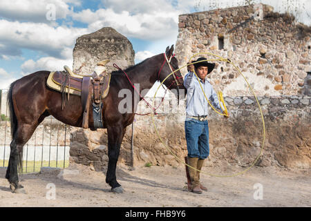 Un Mexicain charro ou pratiques cowboy roping compétences avec son cheval à une hacienda ranch dans Alcocer, au Mexique. La Charreada est une forme traditionnelle mexicaine de rodeo et teste les compétences de l'équitation à cowboy au lasso, et le contrôle du bétail. Banque D'Images