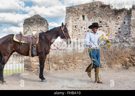 Un Mexicain charro ou pratiques cowboy roping compétences avec son cheval à une hacienda ranch dans Alcocer, au Mexique. La Charreada est une forme traditionnelle mexicaine de rodeo et teste les compétences de l'équitation à cowboy au lasso, et le contrôle du bétail. Banque D'Images