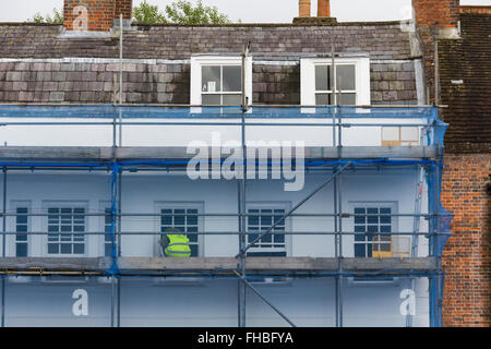 Décorateur travaillant sur le mur extérieur de l'échafaudage et compensation de débris entourant un immeuble sur High Street Marlborough, Royaume-Uni Banque D'Images