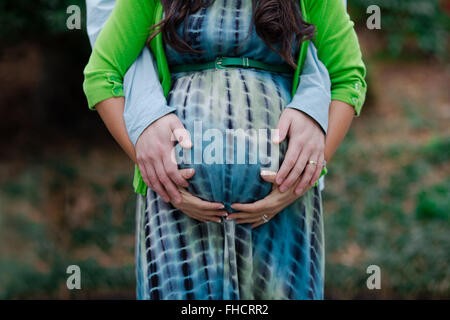 Femme enceinte avec mari holding belly Banque D'Images