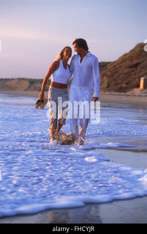 Couple amoureux profiter promenade romantique à travers les vagues de la plage le long de la côte de la Californie au coucher du soleil Banque D'Images