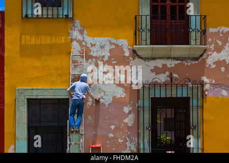 Un peintre au travail dans la maisons peintes de couleurs vives et boutiques bordent les rues à Oaxaca, Mexique Banque D'Images