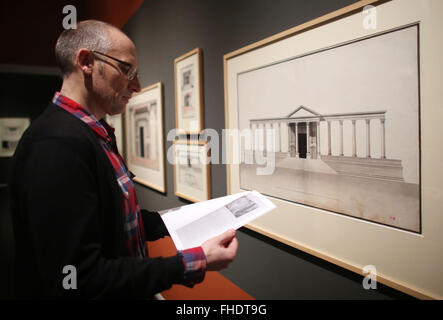 Cologne, Allemagne. Feb 23, 2016. Un homme feuillette un catalogue comme il se place devant un graphique représentant un camp de Dioclétien dans l'exposition 'Palmyra - Was bleibt ?' (Palmyra - que reste-t-il ?) à l'Wallraf Richartz Museum de Cologne, Allemagne, 23 février 2016. L'exposition, qui se déroulera du 26 février au 08 mai 2016, mettra en vedette graphiques par Louis-Francois Cassas de lors de sa visite à Palmyre. Photo : OLIVER BERG/dpa/Alamy Live News Banque D'Images