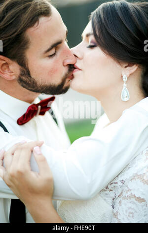 Mariée et le marié baiser. Couple de jeunes mariés, baiser. Fermer portrait. L'homme en dentelle avec bretelles. Banque D'Images
