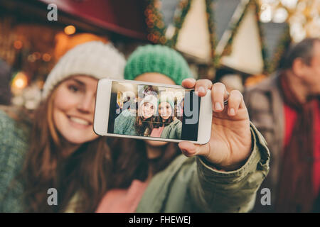 Deux heureux femmes prenant une sur le marché de Noël selfies Banque D'Images