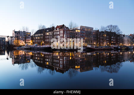 Vue le long du Canal Oudeschans à Amsterdam au crépuscule. Des capacités, des bateaux et des réflexions peuvent être vus. Il y a de l'espace pour le texte Banque D'Images