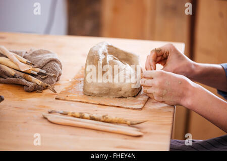 Libre de mains de jeune femme et de travail de l'artiste céramiste sculpture de finition avec de l'argile sur table en bois en atelier Banque D'Images