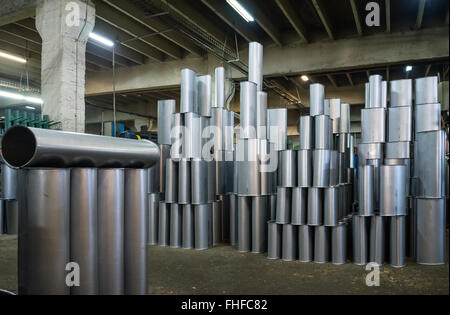 Close-up de tubes métalliques en argent fabriqués empilés à la verticale, sur le sol d'un hall industriel Banque D'Images