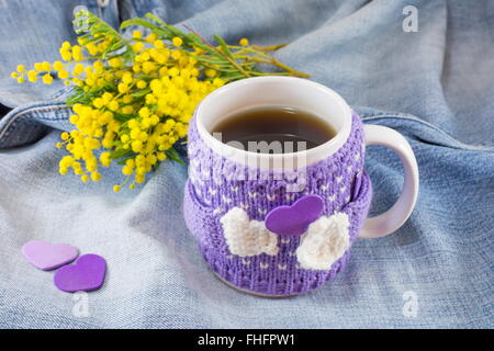Tasse de thé d'hiver et mimosa fleurs sur fond bleu denim Banque D'Images