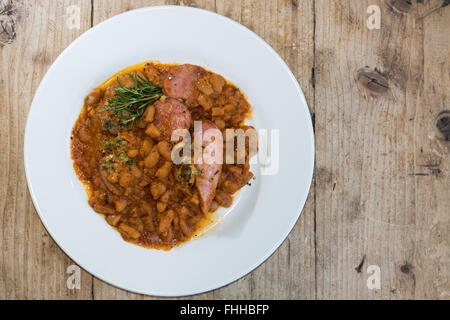 Cassoulet Toulousain à partir de ci-dessus. Restaurant de cuisine française préparée avec des haricots ragoût et une variété de saucisses de porc, servi avec le romarin Banque D'Images