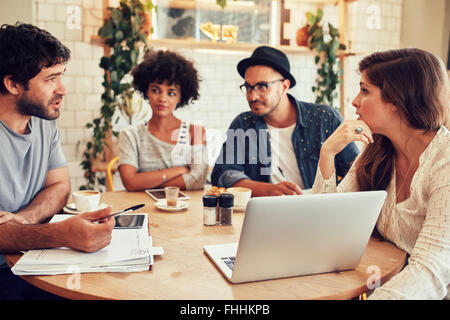 Portrait de jeunes gens assis autour de café avec un ordinateur portable. Réunion de l'équipe de Créatifs dans un café pour discuter de nouveau busines Banque D'Images