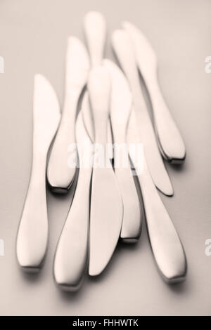 Monochromatique aux tons noir et blanc, b&w, couteaux en métal de la table, argenterie, regroupées et tourné sur un fond clair. Shot selective focus Banque D'Images
