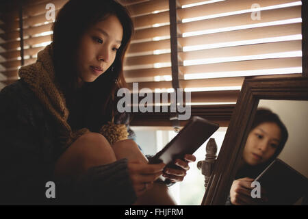 Brunette assise sur le bord de la fenêtre à l'aide de tablet Banque D'Images