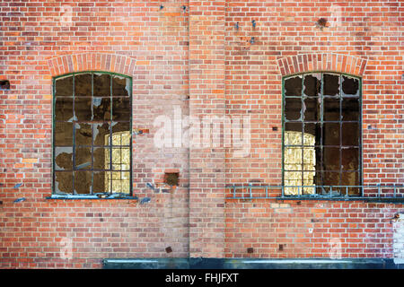 Broken windows sur un vieux bâtiment industriel et abandonnés. L'ancienne usine est faite de briques rouges. Banque D'Images