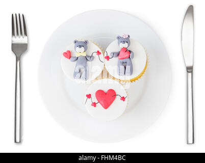 Cupcakes avec ours en peluche et les coeurs sur la plaque isolé sur fond blanc. L'amour plat. Banque D'Images