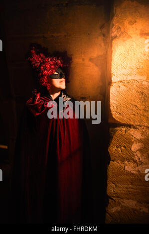 Figure féminine portant perruque rouge debout dans château par la fenêtre Banque D'Images