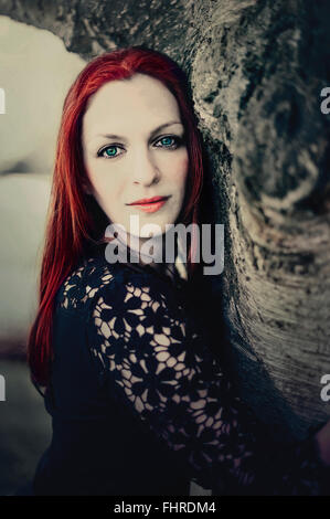 Portrait de la femme de cheveux rouge par l'arbre