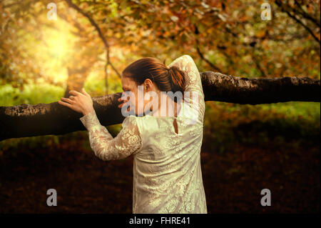 Jeune femme en se penchant sur la branche d'arbre du parc Banque D'Images