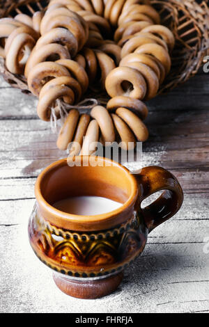 Des Bagels et verre de lait sur fond parsemé de farine dans le style slave Banque D'Images