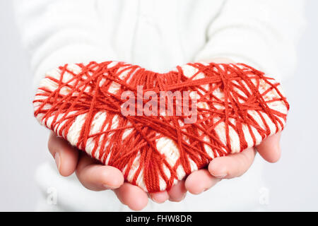 Femme mains donnant un coeur en tricot. Un symbole de la saint valentin et l'amour. Knitwork de fête Banque D'Images