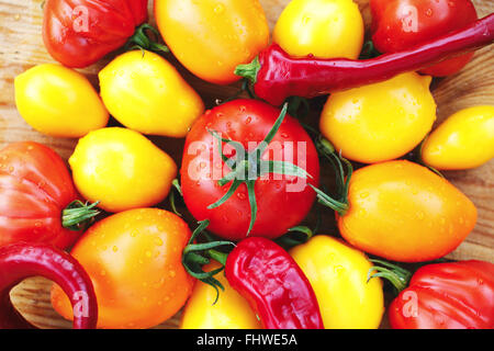 Assortiment de tomates biologiques fraîches sur un fond de bois avec des poivrons Banque D'Images