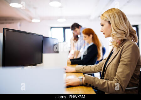 Businesswoman using computer in office while sitting at desk Banque D'Images