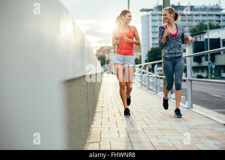 Belles femmes jogging en ville tout en soleil se couche vers le bas Banque D'Images