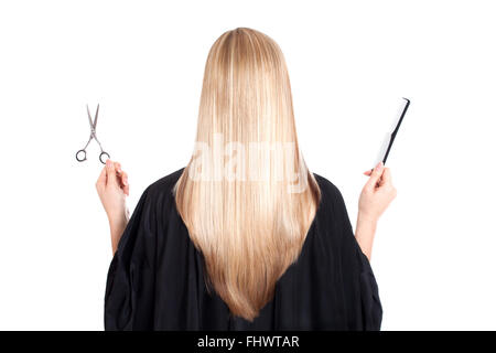 Une femme blonde sur fond blanc tenant des ciseaux dans la main gauche et un noir peigne dans son droit. Elle a beau, long et h Banque D'Images