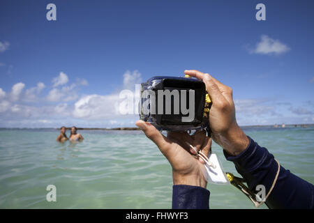 Les touristes étant photographiés au cours de marcher sur les récifs coralliens à Maragogi Beach Banque D'Images