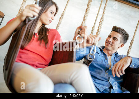 Young couple relaxing in swing tout en parlant et le flirt Banque D'Images