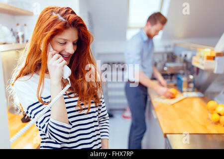 Gorgeus ginger femme parlant au téléphone dans la cuisine Banque D'Images