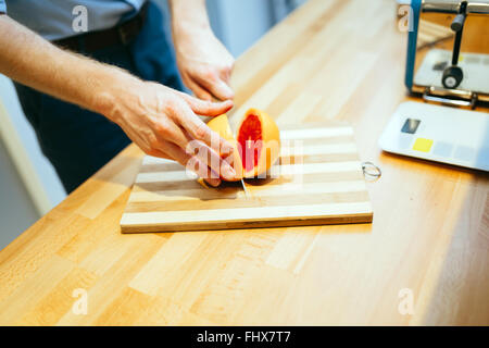 Man slicing en orange avec un couteau de cuisine Banque D'Images