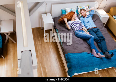 Beautiful couple resting on lit dans un appartement moderne Banque D'Images