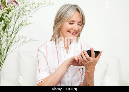 Hauts femme jouant un jeu en ligne sur smartphone Banque D'Images