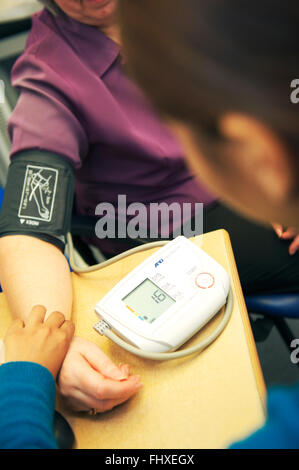 Médecin prend la pression artérielle des patients dans un centre de santé au Royaume-Uni Banque D'Images