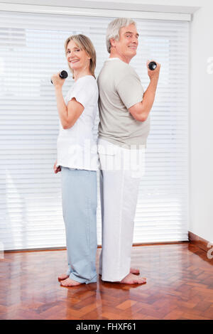 Happy senior couple doing dumbbell exercices en salle de sport Banque D'Images