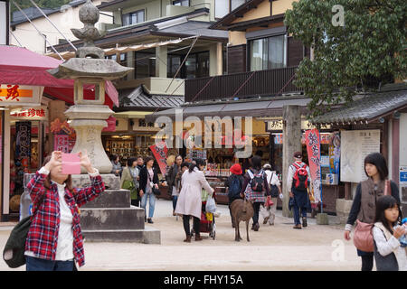 Les touristes visitant les magasins et apprivoiser le cerf sur l'île de Miyajima, Hiroshima, Japon Banque D'Images