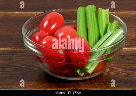 Les tomates cerise avec le céleri dans un bol sur la table en bois Banque D'Images