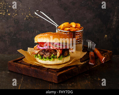 Burger à la viande et les quartiers de pommes de terre sur fond sombre Banque D'Images