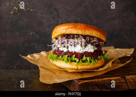 Burger de betterave avec fromage doux et pousses de radis sur fond sombre Banque D'Images