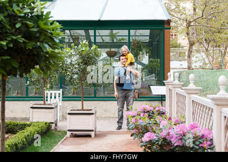 Fille assise sur les épaules de Papa dans le jardin Banque D'Images