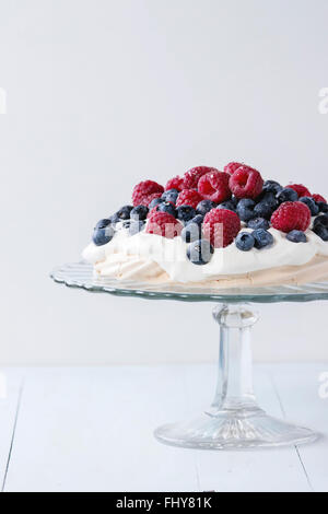 Vintage cake stand avec de la meringue dessert Pavlova avec des mûres et framboises sur table en bois bleu. Banque D'Images