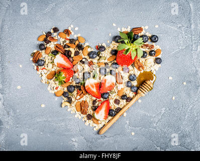 Ingrédients pour la cuisson petit déjeuner sain du muesli en forme de coeur. Les écrous des bleuets fraises fruits secs flocons d'avoine Banque D'Images