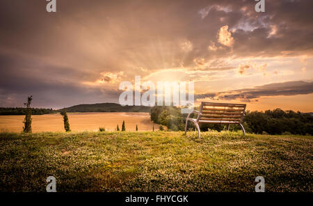 Magnifique coucher de soleil paysage avec banc solitaire à l'avant-plan Banque D'Images