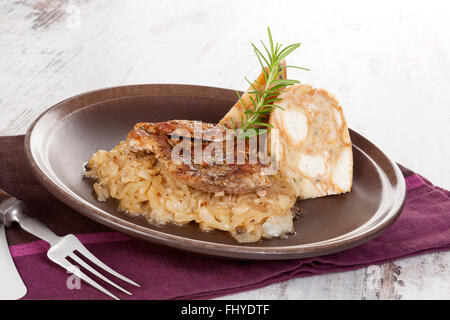 Côtelette de porc cuit au four avec des boulettes et de la choucroute sur la plaque avec des couverts en argent sur table en bois. Banque D'Images