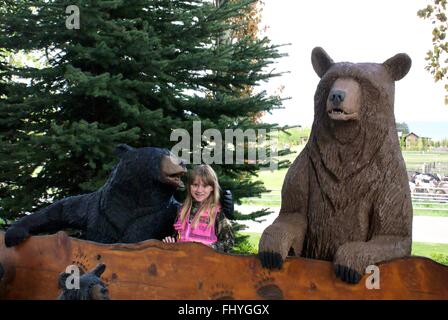 Petite fille avec des ours en bois sculpté à la Snake River Resort de Jackson Hole, Wyoming. Banque D'Images