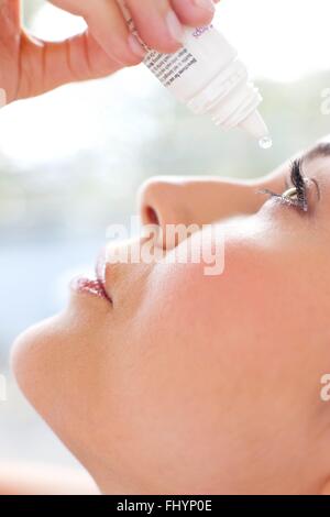 Parution du modèle. Femme à l'aide de gouttes pour les yeux. Banque D'Images