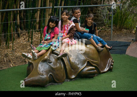 Quatre jeunes filles s'asseoir sur un métal sculpté hippopotame au zoo de SAN DIEGO - Californie Banque D'Images